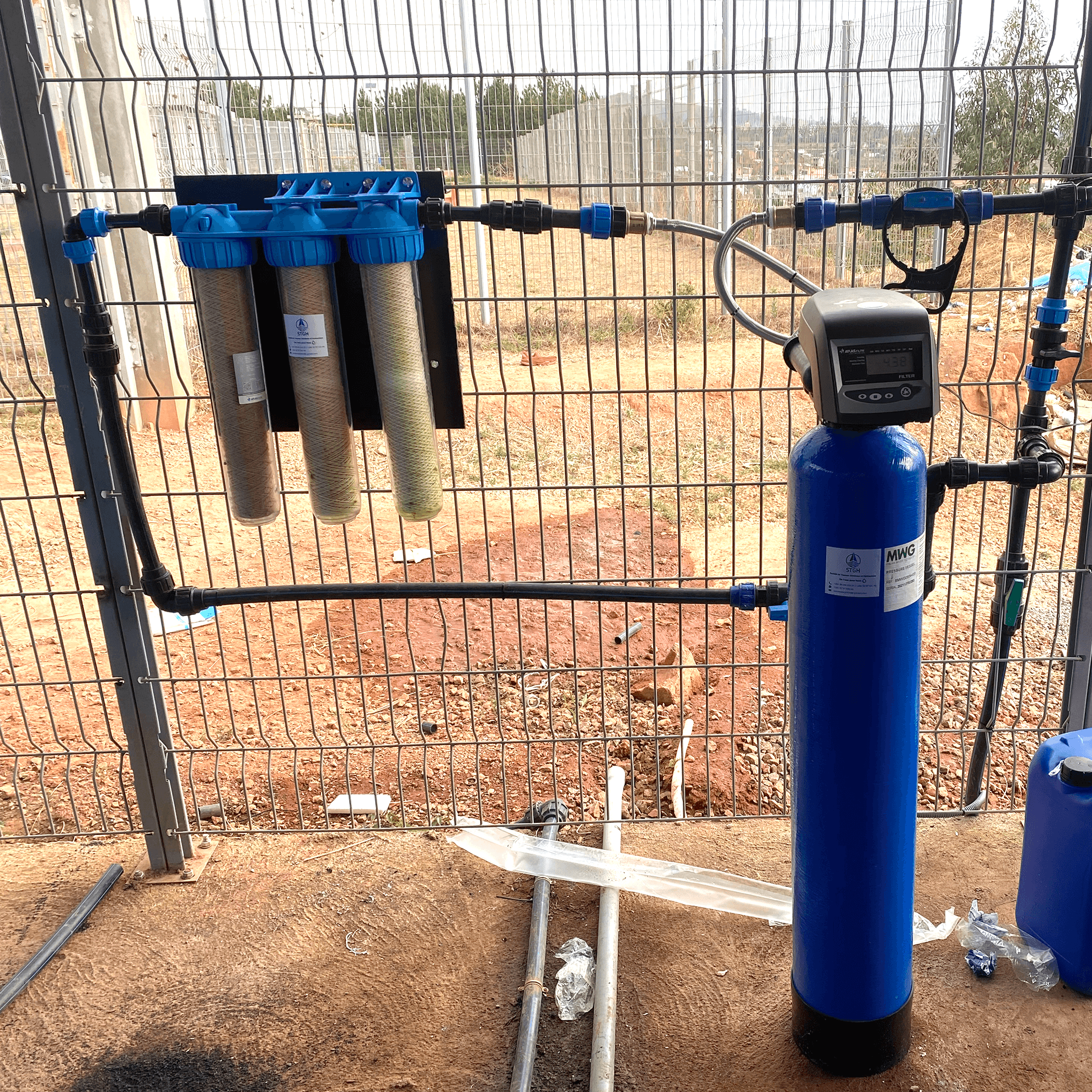Trois filtres a cartouches et une bouteille de resine utilises pour le pretraitement de l'eau avant osmose inverse.
